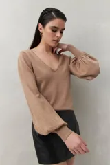 Top negro de tejido sutilmente metalizado, con escote en V y mangas abullonadas.