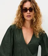 Mono largo verde oscuro de microfibra texturizada, con escote en V cruzado, mangas largas amplias con puños elásticos y lazo ajustable en la cintura. Presenta diseño de piernas rectas y caída fluida.