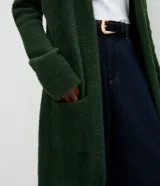 Cardigan largo de punto con textura de pelos, color negro, con mangas largas y bolsillos frontales. Diseño abierto y versátil de la marca Cortelle.