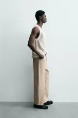 Chaleco de punto color blanco roto, con cuello redondo y sisa, confeccionado en tejido calado de estructura abierta y acabado en rib.