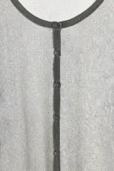 Chaqueta gris de punto fino semitransparente con hilo metalizado, cuello redondo, manga larga y cierre frontal con botones.
