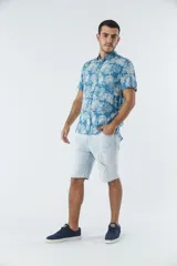 Camisa de manga corta con estampado botánico de hojas en tonos azul y blanco. Presenta cuello clásico, cierre frontal abotonado y corte slim.