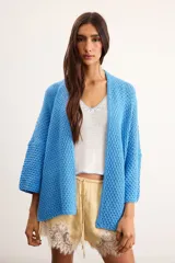 Cardigan oversize tejido de punto color celeste, con diseño abierto sin botones, mangas caídas y corte amplio.