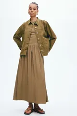 Campera camisera de sarga de algodón color verde militar, con cuello clásico, cierre frontal de botones metálicos, canesú y bolsillos de parche delanteros.