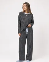 Pijama set de dos piezas compuesto por una remera de manga larga a rayas horizontales con cuello redondo celeste, y un pantalón largo de corte holgado a rayas verticales con cordón de ajuste en la cintura.