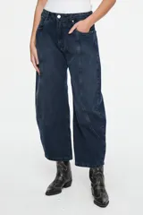 Pantalón de denim azul oscuro con corte balloon, tiro medio, costuras curvas decorativas en el frente y diseño de cinco bolsillos.