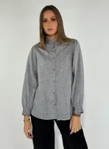 Camisa color beige con cuello mao, mangas largas abullonadas y cierre frontal con botones.