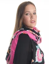 Pashmina estampada con diseño floral en tonos rosados, fucsias y verdes sobre fondo negro. Presenta terminaciones desflecadas en los bordes y está confeccionada en tejido ligero tipo gasa.