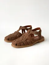 Sandalias de cuero gamuzado color marrón chocolate, diseño tipo huarache con tiras entrelazadas, tira en el empeine, talón cerrado y hebilla metálica de ajuste lateral.