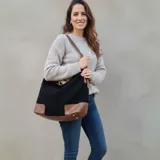 Bolso tipo hobo de eco cuero con textura símil gamuza color marrón rojizo. Presenta detalles de cuero liso color caramelo en la base y tiras ajustables en los laterales.