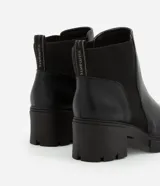 Bota Chelsea color negro, confeccionada en poliuretano, con detalle elástico acanalado en los laterales y suela track.