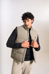 Chaleco puffer de corte regular, color beige, con cuello alto, cierre frontal completo y logo bordado en el pecho.