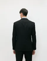 Ambo negro de corte clásico para hombre, compuesto por saco de solapas de muesca con dos botones, chaleco abotonado a juego y pantalón de vestir de corte recto.