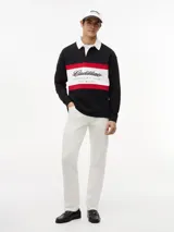 Chomba de rugby de manga larga Tommy Hilfiger en colaboración con Cadillac Formula 1 Team. Presenta un diseño en bloques de color negro, blanco y rojo, con cuello estilo rugby en color blanco y cierre frontal oculto. Incluye el logo de Cadillac en fuente script y el logo de Tommy Hilfiger estampados en el pecho.