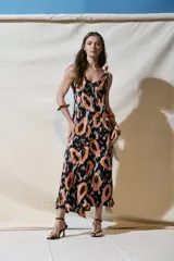 Vestido largo de viscosa con estampado de papayas en tonos naranja, rosa y blanco sobre fondo negro. Tiene escote en V tanto en la parte delantera como en la trasera, tirantes finos y corte holgado.