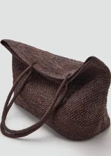 Bolso tipo shopper color marrón, confeccionado en paja trenzada con dos asas largas para llevar al hombro.