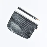 Sobre de mano negro con textura símil cuero de cocodrilo y correa de muñeca desmontable.