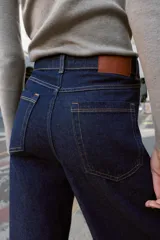 Jeans de tiro alto con pernera ancha y diseño combinado en dos tonos de denim. El panel central es de un lavado azul medio, mientras que los paneles laterales son de un lavado azul oscuro. Presenta cinco bolsillos y cierre frontal con cremallera y botón.