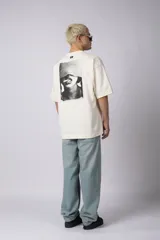 Remera de corte oversize confeccionada en algodón premium de alto gramaje. Presenta un diseño minimalista con un pequeño logo bordado en el centro del pecho y un parche estampado en la espalda. Posee cuello redondo y mangas cortas con caída relajada.