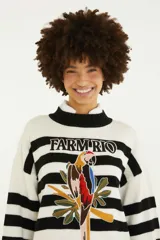 Sweater de punto con diseño a rayas horizontales blancas y negras, cuello alto y puños anchos. Cuenta con un bordado frontal en el centro que representa un loro sobre hojas tropicales y el texto "Farm Rio".