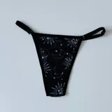 Tanga negra de microtul con estampado de lunas, soles y estrellas.