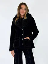 Chaqueta de denim azul oscuro con cuello de piel sintética desmontable, cierre frontal con botones metálicos y bolsillos delanteros con solapa.