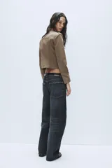 Jeans de tiro medio con diseño baggy barrel, confeccionados en denim color beige con efecto lavado. Presentan cinco bolsillos, costuras laterales torcidas y cierre frontal con cremallera y botón metálico.