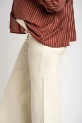 Pantalón de jean color beige, de corte wide leg con botamanga desflecada y tiro medio, diseñado especialmente para maternidad.