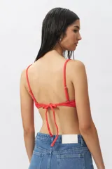 Top de bikini color coral/rojo con textura acanalada y un aro metálico en el centro del escote. Posee tirantes finos ajustables y copas removibles.