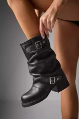 Botas negras de cuero vegano con caña arrugada y dos correas con hebillas metálicas.