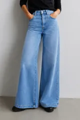 Jean de tiro alto con corte wide leg, confeccionado en denim con elastano. Presenta un lavado celeste suave, diseño de pierna extra amplia y cierre frontal con botón y cremallera.