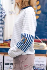 Remera de manga larga con corte boxy, confeccionada en algodón. Presenta un diseño a rayas horizontales celestes y blancas, con puños en contraste azul oscuro, tajos laterales y logo bordado en el pecho.