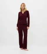 Pijama largo de dos piezas marca Lov, confeccionado en tejido rib de poliéster con elastano. La blusa es de manga larga estilo americano con cuello solapa y cierre frontal de botones. El pantalón es de corte recto con cintura satinada.