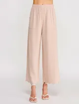 Pantalón palazzo de tiro alto color beige, confeccionado en mezcla de lino y viscosa, con silueta suelta y fluida, cintura elastizada, bolsillos delanteros aplicados y ruedo festoneado de corte tobillero.