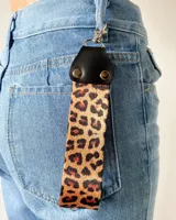 Llavero con correa de tela con estampado animal print y detalles en cuero sintético negro.