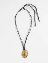 Collar con cordón negro y dije dorado con forma orgánica irregular.