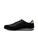 Zapatilla deportiva de mujer, estilo retro running, en tonos negro y blanco. Presenta una combinación de materiales, incluyendo cuero liso negro en el cuerpo principal, gamuza negra en la puntera y talón, y un detalle de cuero blanco en el contrafuerte del talón. Cordones blancos y suela bicolor (blanco y negro).