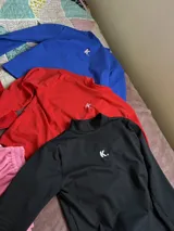 Polera de manga larga, cuello alto y corte crop, color azul Francia, confeccionada en lycra premium con un pequeño logo bordado en color rosa en el pecho.