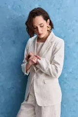 Blazer color beige claro, de corte clásico con solapa, cierre de un botón y bolsillos delanteros de vivo.