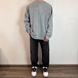 Buzo de cuello redondo con corte oversize, confeccionado en tela con efecto lavado ácido. Presenta costuras reforzadas visibles y una pequeña etiqueta con logo en el puño.