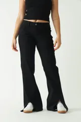 Pantalón negro de tiro medio, corte ajustado en la cadera y piernas que se ensanchan. Presenta cortes en el bajo de cada pierna.