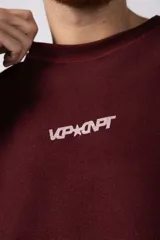 Buzo de cuello redondo confeccionado en tejido rústico con bordes al corte y costuras expuestas. Presenta un diseño boxy con estampado frontal y es reversible, permitiendo su uso por ambos lados.