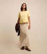 Blusa amarilla de mangas cortas con cuello redondo y bajo con flores bordadas.