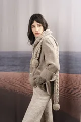 Bufanda tejida a mano en punto arroz color crudo, con detalle de pompón en uno de los extremos.