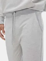 Pantalón tipo babucha de color azul oscuro, confeccionado con interior de felpa. Presenta cintura elástica con cordón de ajuste y puños acanalados en los tobillos.