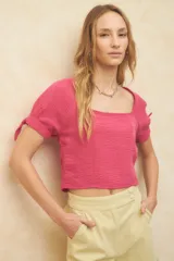 Top corto color blanco roto, con escote cuadrado, manga corta abullonada con lazos ajustables en el borde y textura arrugada en el tejido.