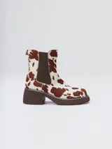 Bota tipo chelsea de cuero vacuno en color rojo con estampado floral grabado en negro. Presenta paneles laterales elásticos, suela de plataforma y taco cuadrado en color negro.