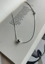 Collar plateado con dije esférico plateado.