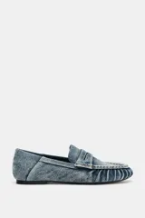 Mocasín plano confeccionado en efecto denim, con diseño de antifaz en el empeine, detalles fruncidos en la parte delantera y punta redonda.