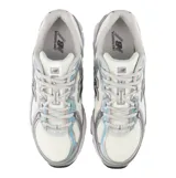 Championes New Balance modelo 740, con diseño retro inspirado en el running de los años 2000. Presentan una capellada de malla transpirable en color blanco con superposiciones sintéticas en gris y detalles en azul claro. Incluyen entresuela con tecnología ABZORB para absorción de impactos y suela de goma resistente.